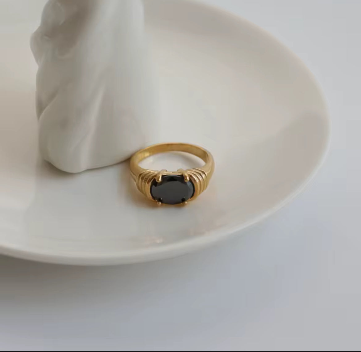 Gold ring with a black stone on a white plate
