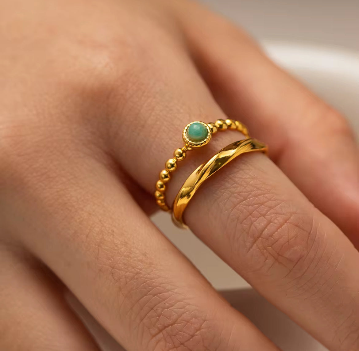 Gold ring with a green gemstone on a person's finger
