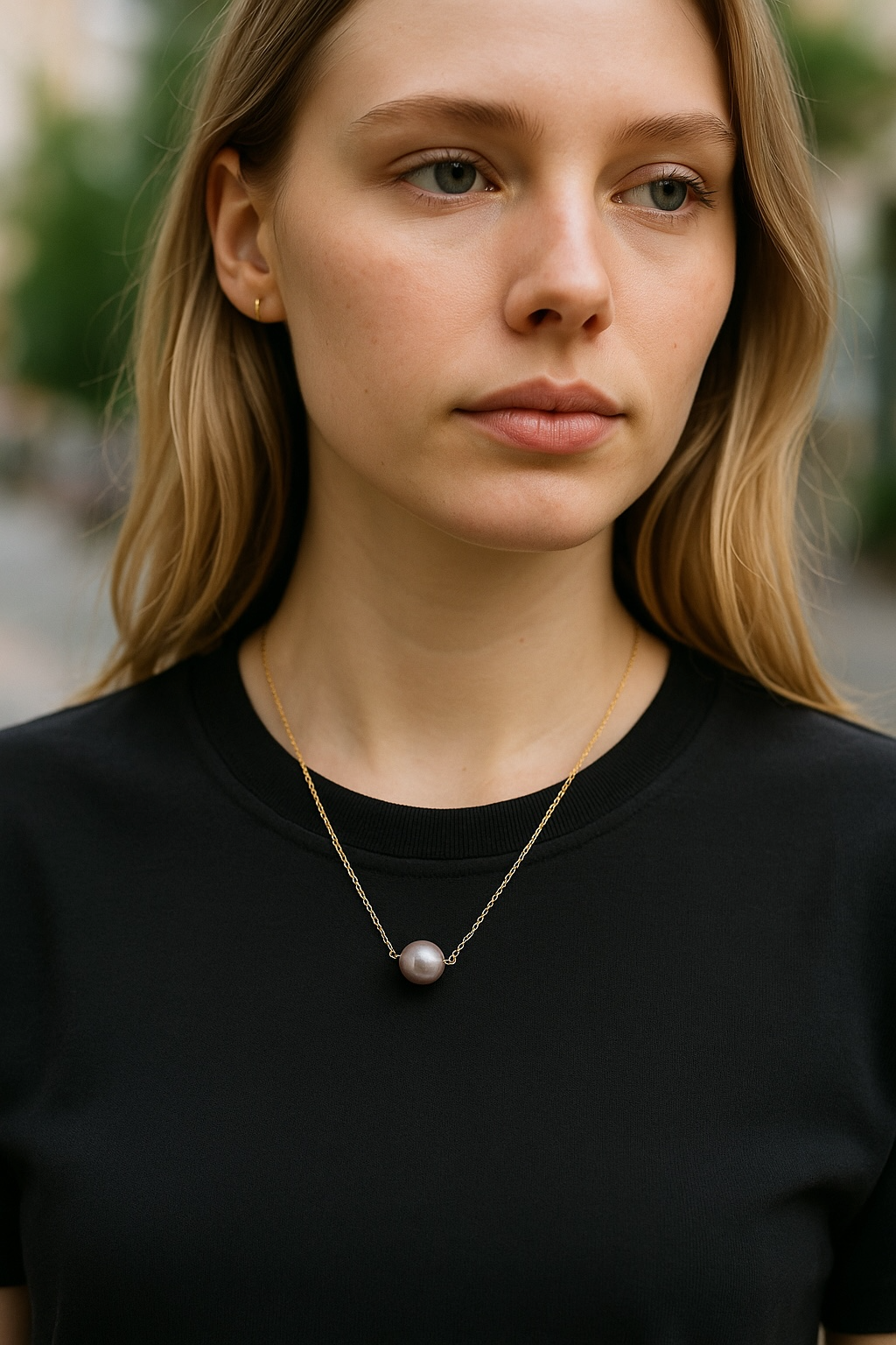 A woman wearing a black shirt and a purple  round pearl necklace 