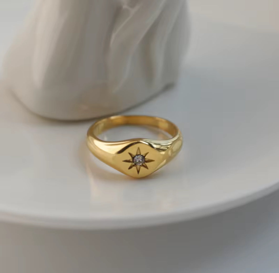 Gold ring with a star design on a white surface