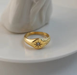 Gold ring with a star design on a white surface