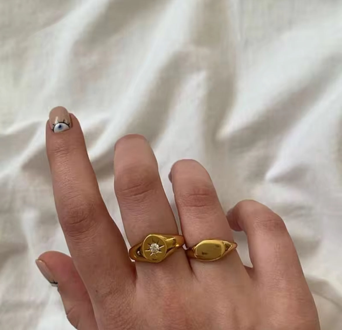 Gold ring on a finger against a white fabric background