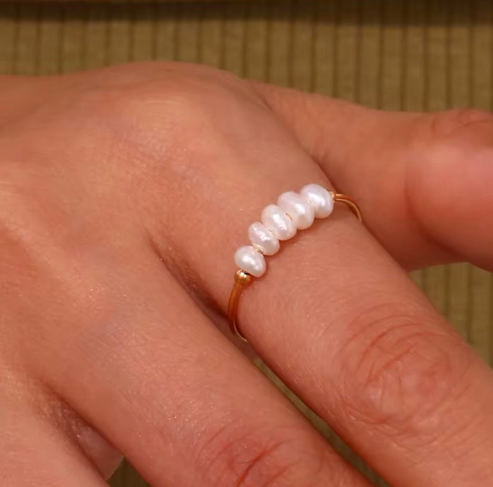 Pearl ring on a person's finger with a neutral background