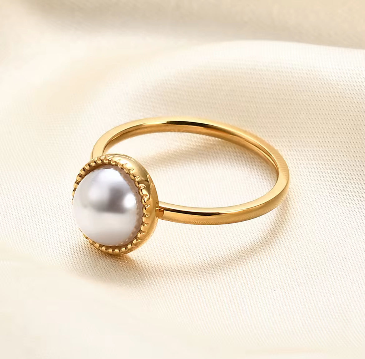 Gold ring with a pearl on a light fabric background