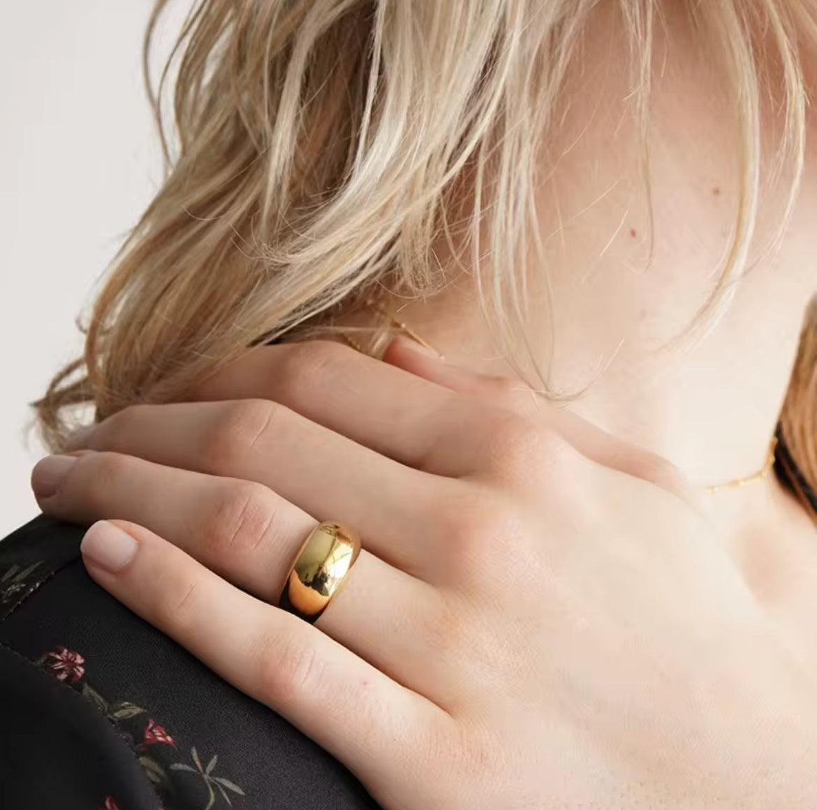 Close-up of a hand wearing a gold ring with a blurred background