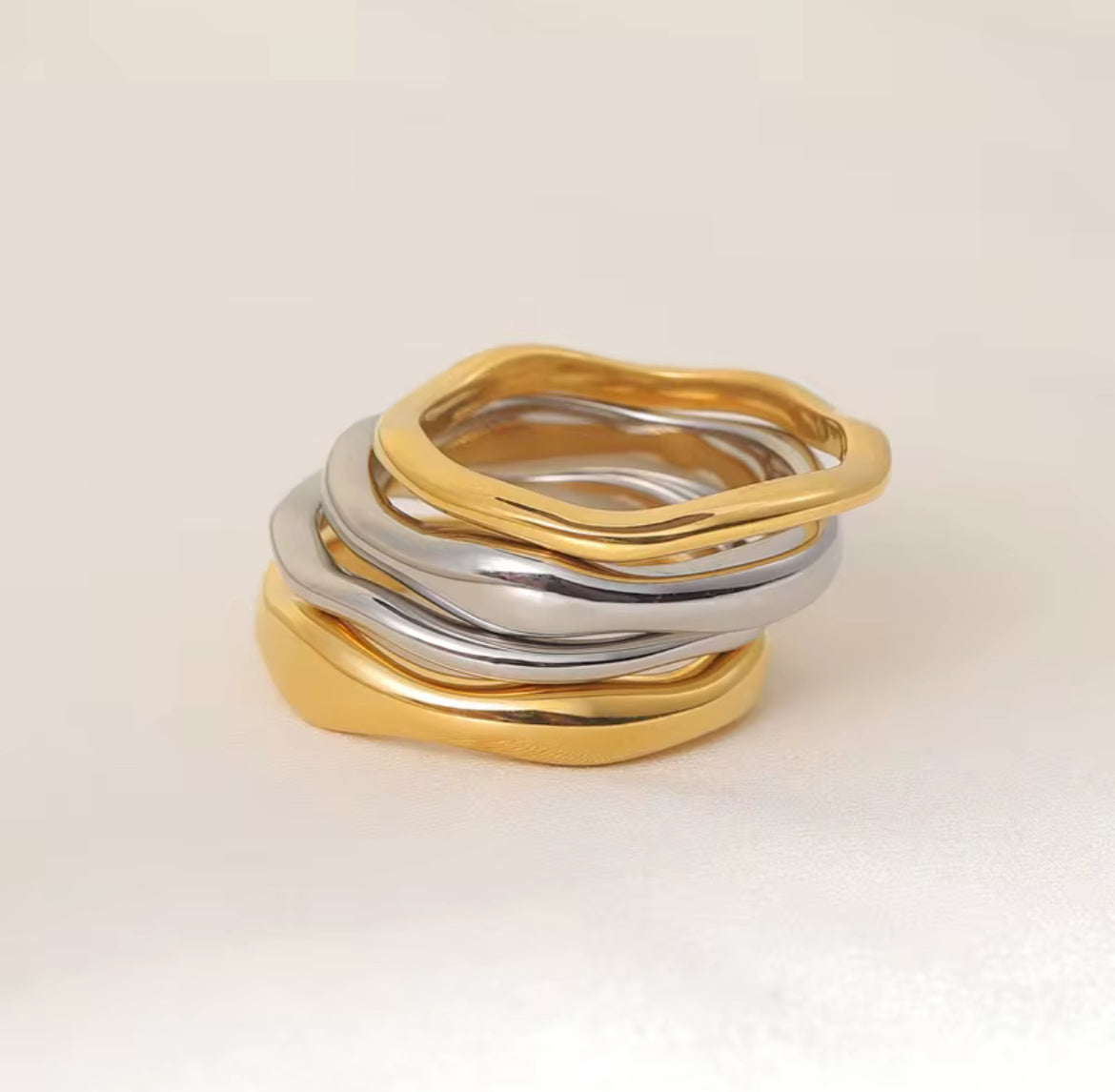 Stack of gold and silver rings on a beige background