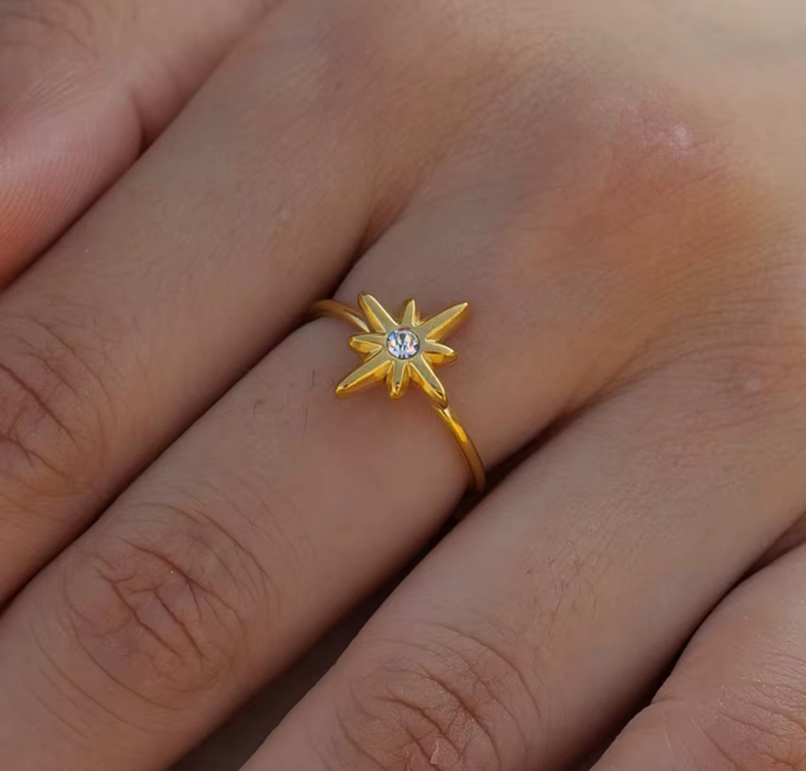 Gold star-shaped ring with a diamond on a person's finger