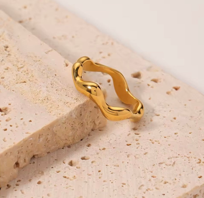 Gold ring with a unique design on a textured beige surface