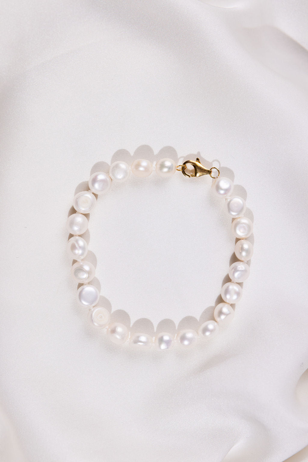 White Pearl bracelet with a gold clasp on a white background