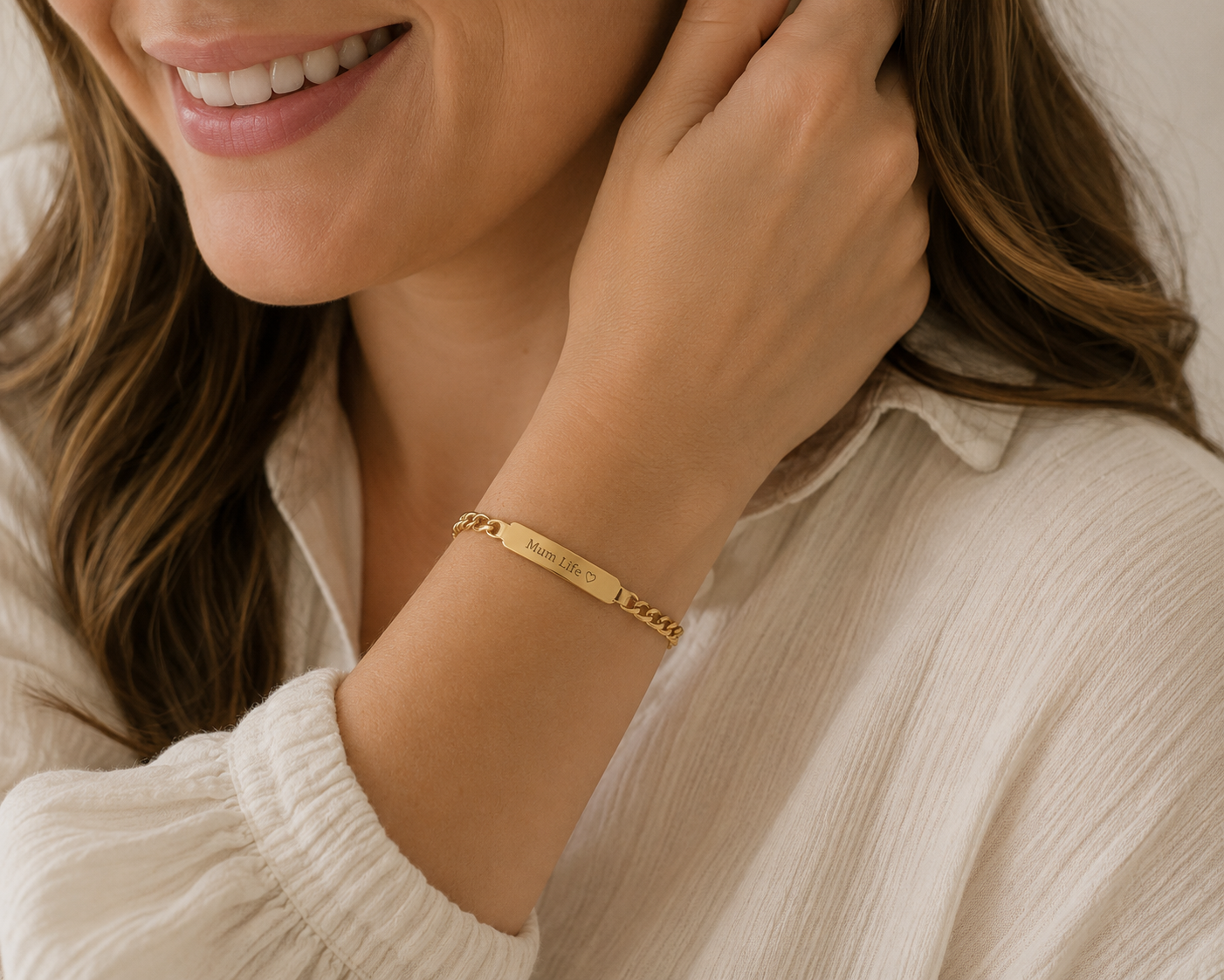 Woman wearing a gold bracelet with a visible brand name, smiling.