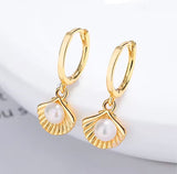Gold hoop earrings with pearl drops on a light background